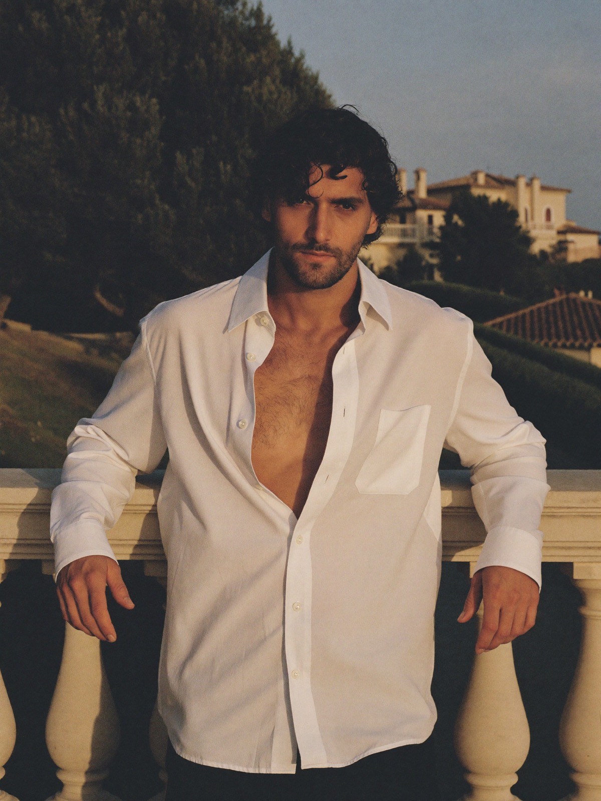 Teo, portrait leaning on a villa balustrade at golden hour