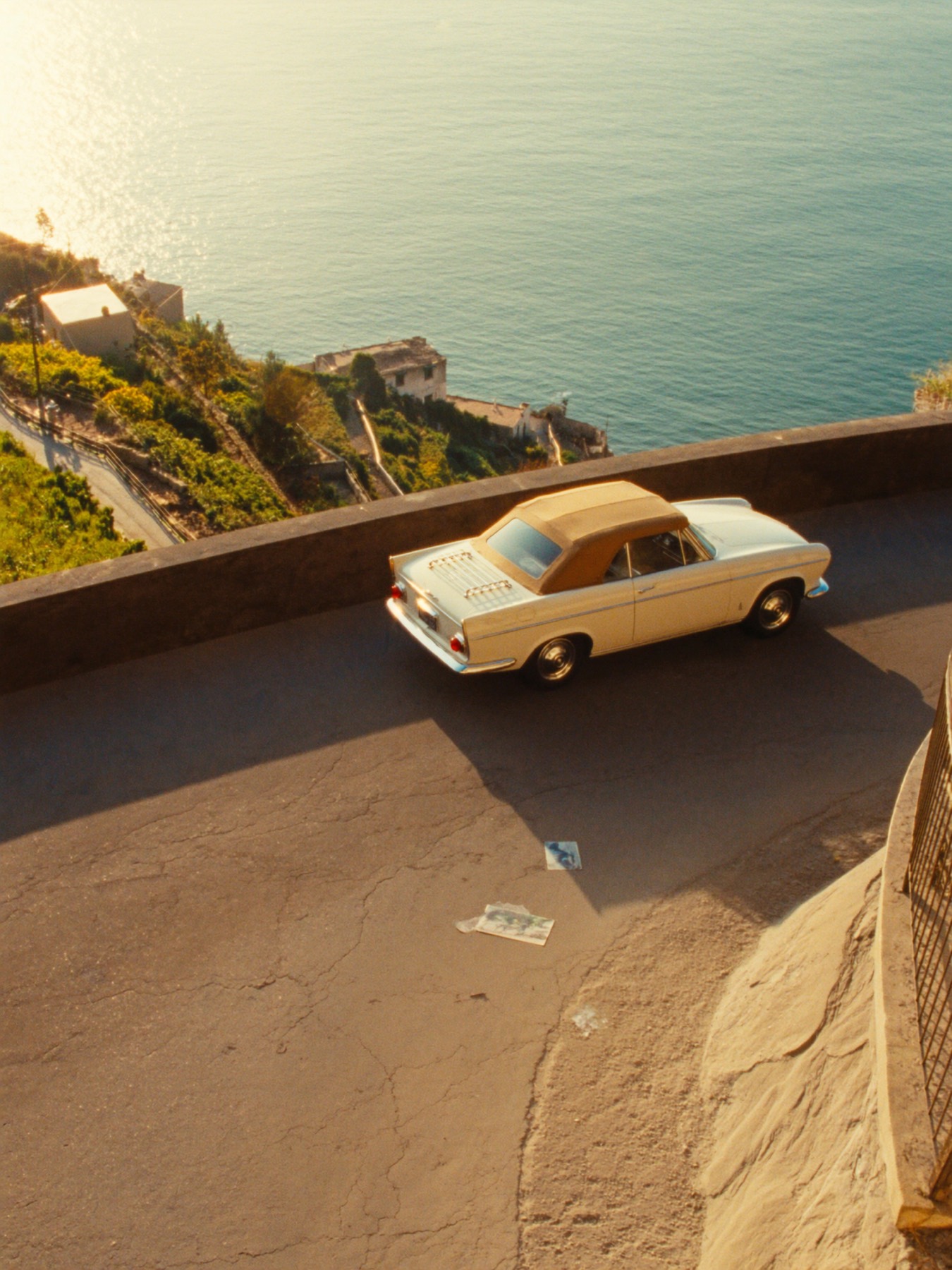 A vintage convertible parked on a cliffside bend of the Amalfi coast at golden hour